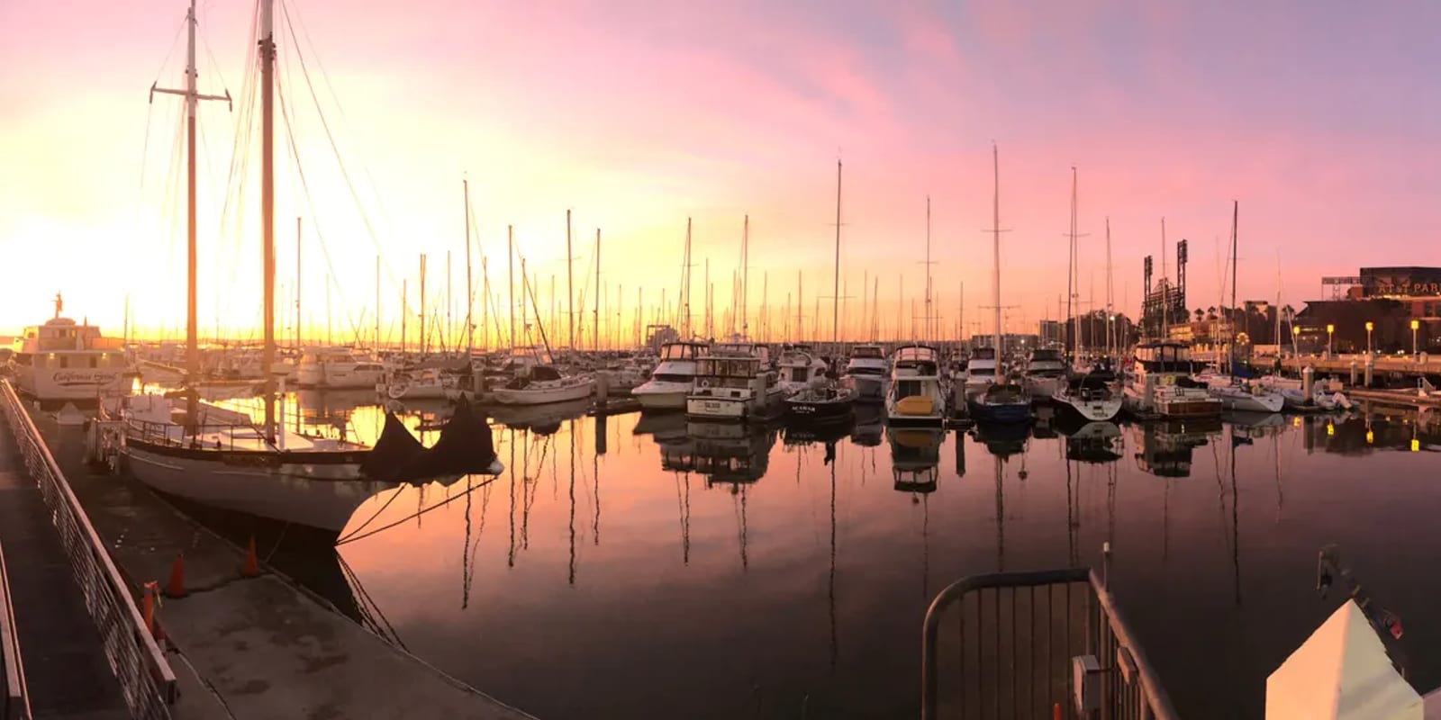 Sailboats at their berths in South Beach Harbor at sunset, masts reflected in still water